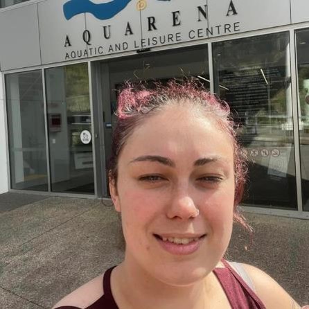 A woman takes a selfie in front of a building.