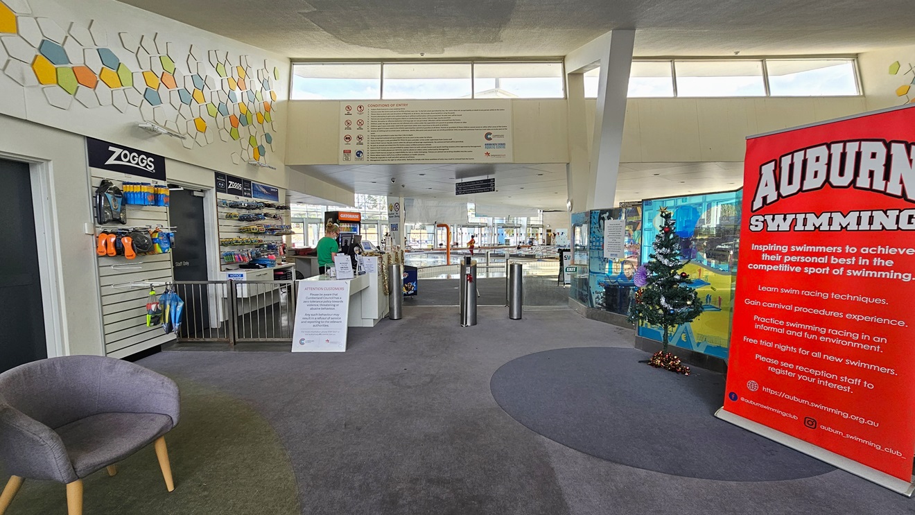 Manual inward-opening glass door at Auburn Ruth Everuss Aquatic Centre. On the upper left of the glass front wall are the conditions of entry, highlighting the prohibited activities as represented by the logos on the left. A No Smoking sign, 24/7 CCTV monitoring, and a Hiring sign are affixed to the glass doors. Information on the time when the public is limited to accessing the 25m and 50m pool is detailed on the white papers. Free entry to the facility is also detailed on the right wall. Manual inward-opening glass door at Auburn Ruth Everuss Aquatic Centre. On the upper left of the glass front wall are the conditions of entry, highlighting the prohibited activities as represented by the logos on the left. A No Smoking sign, 24/7 CCTV monitoring, and a Hiring sign are affixed to the glass doors. Information on the time when the public is limited to accessing the 25m and 50m pool is detailed on the white papers. Free entry to the facility is also detailed on the right wall.