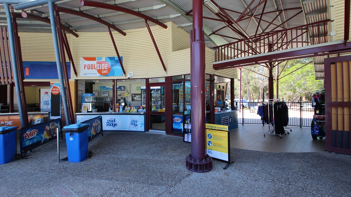 A clearer angle of the reception counter. The low reception counter is to the right and contains a small selection of retail items, including swimming costumes and goggles. A small café is attached to the reception and moves toward the right beyond the reception entry, which is called the poolside café. A clearer angle of the reception counter. The low reception counter is to the right and contains a small selection of retail items, including swimming costumes and goggles. A small café is attached to the reception and moves toward the right beyond the reception entry, which is called the poolside café.
