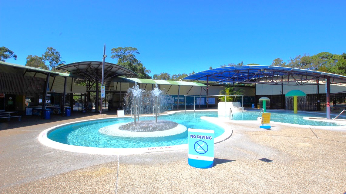 A closer look at the fountain in the open-air aquatic area. It's located right in the center of this pool area, adding a beautiful touch to the surroundings. Just like in other areas, there are signs reminding visitors not to dive. Safety railings can be seen for everyone's safety. On the far right side, there are two mushroom-like decorations, adding a playful element to the pool's atmosphere. A closer look at the fountain in the open-air aquatic area. It's located right in the center of this pool area, adding a beautiful touch to the surroundings. Just like in other areas, there are signs reminding visitors not to dive. Safety railings can be seen for everyone's safety. On the far right side, there are two mushroom-like decorations, adding a playful element to the pool's atmosphere.