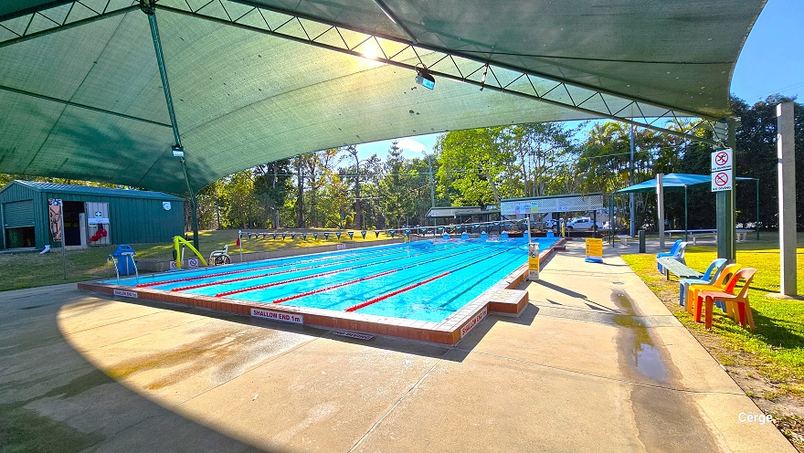 Different angle of the 25m, 6-lane outdoor pool at Dayboro Pool and Gym with partial shading on one end. Seen around the pool are yellow sign boards to remind guests of the do’s and dont’s of the pool. There is a small white sign for No Running and No Diving on a green post on the lawn to the right that has orange and blue monobloc plastic chairs and a grey bench. Different angle of the 25m, 6-lane outdoor pool at Dayboro Pool and Gym with partial shading on one end. Seen around the pool are yellow sign boards to remind guests of the do’s and dont’s of the pool. There is a small white sign for No Running and No Diving on a green post on the lawn to the right that has orange and blue monobloc plastic chairs and a grey bench.