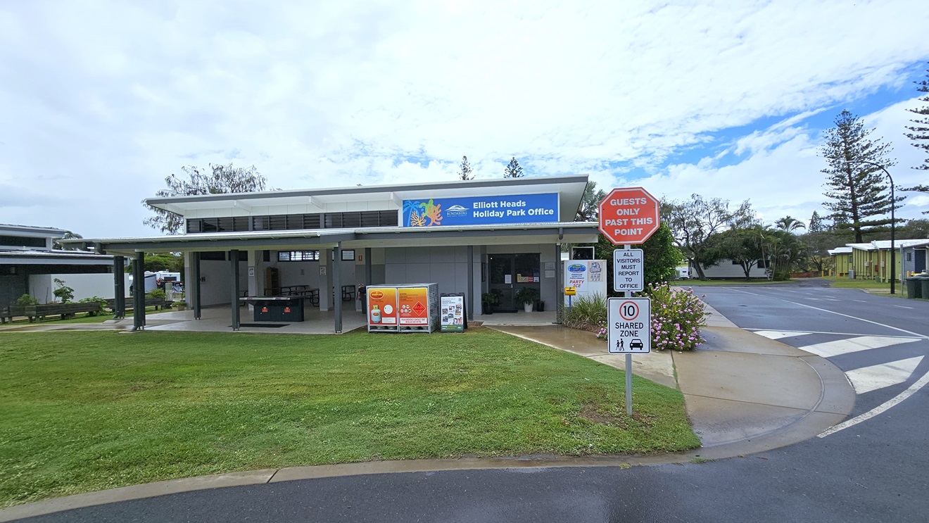 The entrance to the building is a manual glass door opening outward. A black rubber mat and potted plants adorn the front. Posters decorate the walls and door. Inside, the reception desk with a timber front is visible. The interior has wooden floors and a white ceiling with light fixtures. Outside, a tall shrub sits in a concrete planter box. The entrance to the building is a manual glass door opening outward. A black rubber mat and potted plants adorn the front. Posters decorate the walls and door. Inside, the reception desk with a timber front is visible. The interior has wooden floors and a white ceiling with light fixtures. Outside, a tall shrub sits in a concrete planter box.