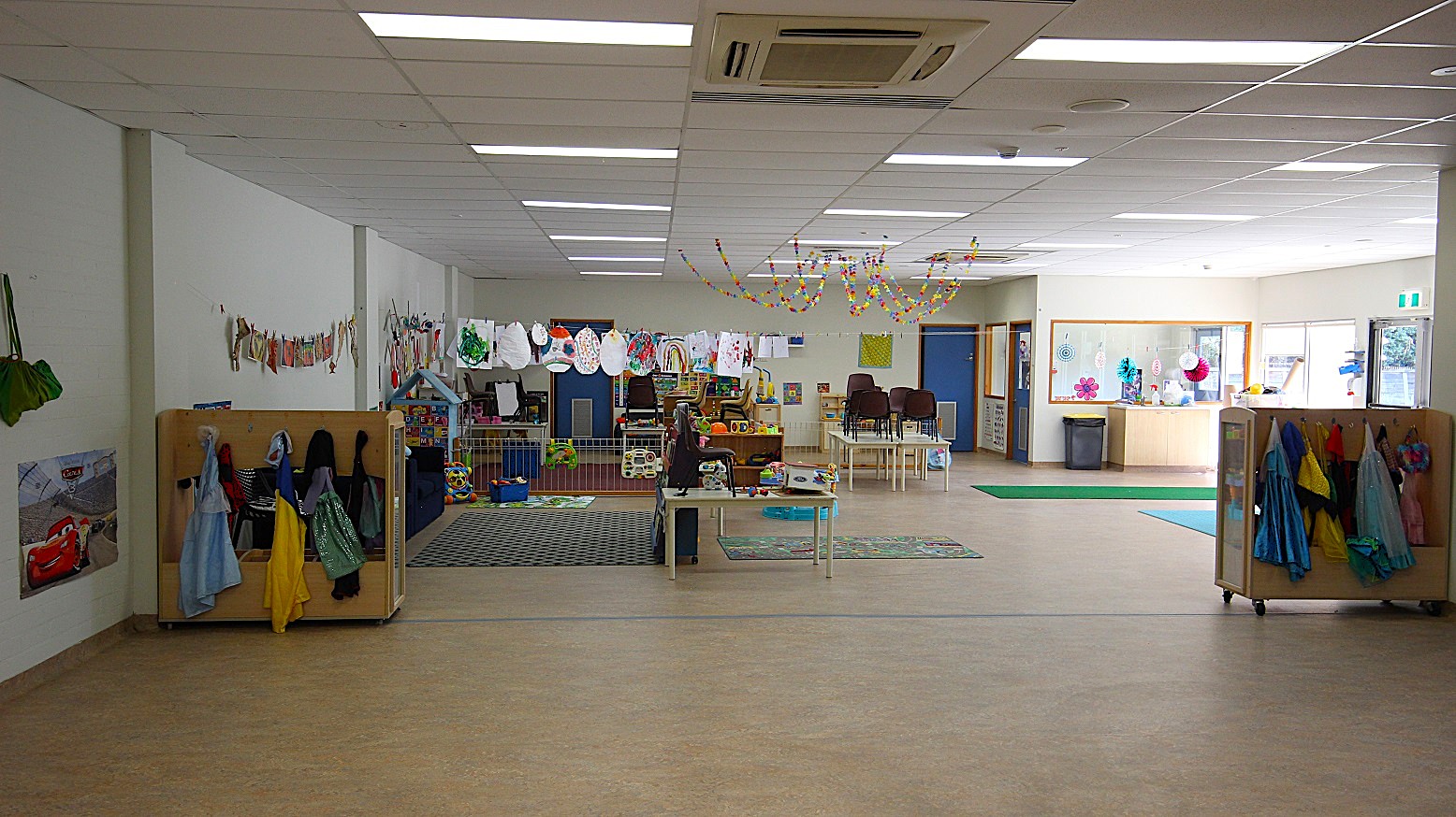 Different costumes for kids are hung in timber-made cabinets. Chairs are arranged carefully at the tables and all toys, drawings, and paintings, are well-organized. Different costumes for kids are hung in timber-made cabinets. Chairs are arranged carefully at the tables and all toys, drawings, and paintings, are well-organized.