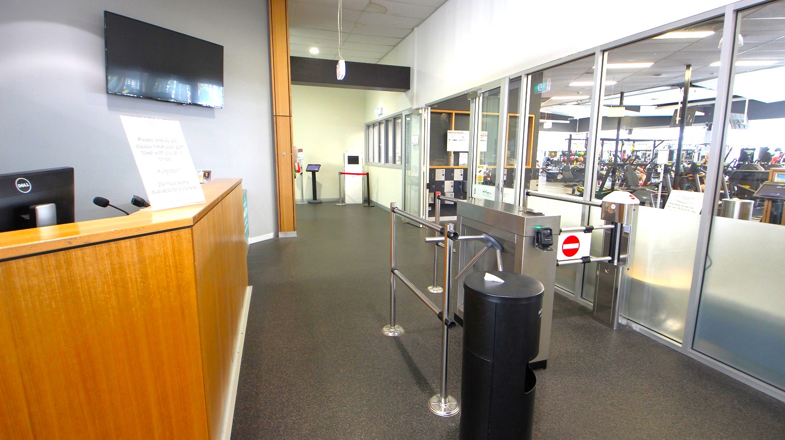 A timber desk and turnstile gates at the entrance of the Gymnasium at Eltham Leisure Centre. The gymnasium has glass walls that entice you with different pieces of equipment available for you to try. A timber desk and turnstile gates at the entrance of the Gymnasium at Eltham Leisure Centre. The gymnasium has glass walls that entice you with different pieces of equipment available for you to try.