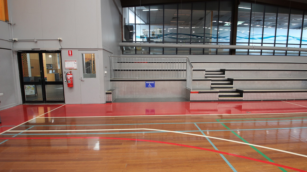 Lower, section of the left and right side of the stadium is a space dedicated or reserved for persons with disability. Further left is the exit door and fire extinguisher mounted on the wall near it. Lower, section of the left and right side of the stadium is a space dedicated or reserved for persons with disability. Further left is the exit door and fire extinguisher mounted on the wall near it.