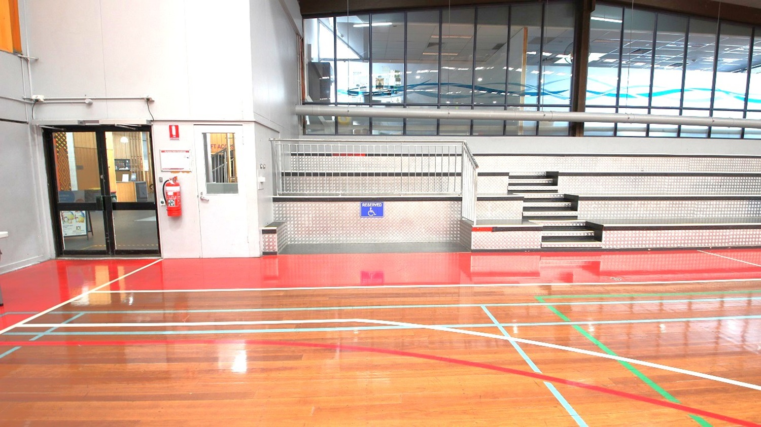 Lower, section of the left and right side of the stadium is a space dedicated or reserved for persons with disability. Further left is the exit door and fire extinguisher mounted on the wall near it. Lower, section of the left and right side of the stadium is a space dedicated or reserved for persons with disability. Further left is the exit door and fire extinguisher mounted on the wall near it.