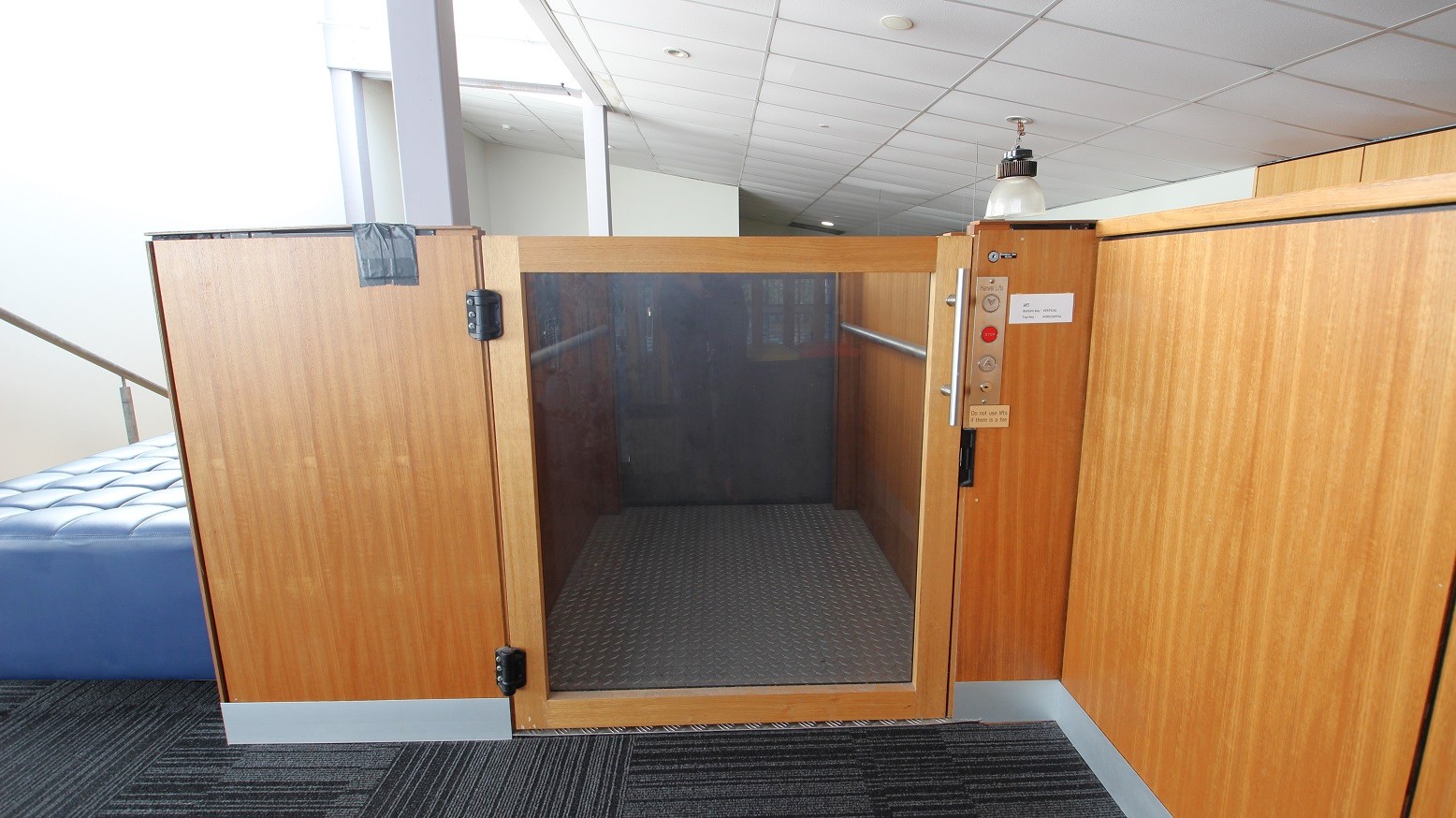 Elevator is made of timber and silver-grey metal and is equipped with Up, Down, and Stop buttons indicated by the red circle in the middle. Elevator is made of timber and silver-grey metal and is equipped with Up, Down, and Stop buttons indicated by the red circle in the middle.