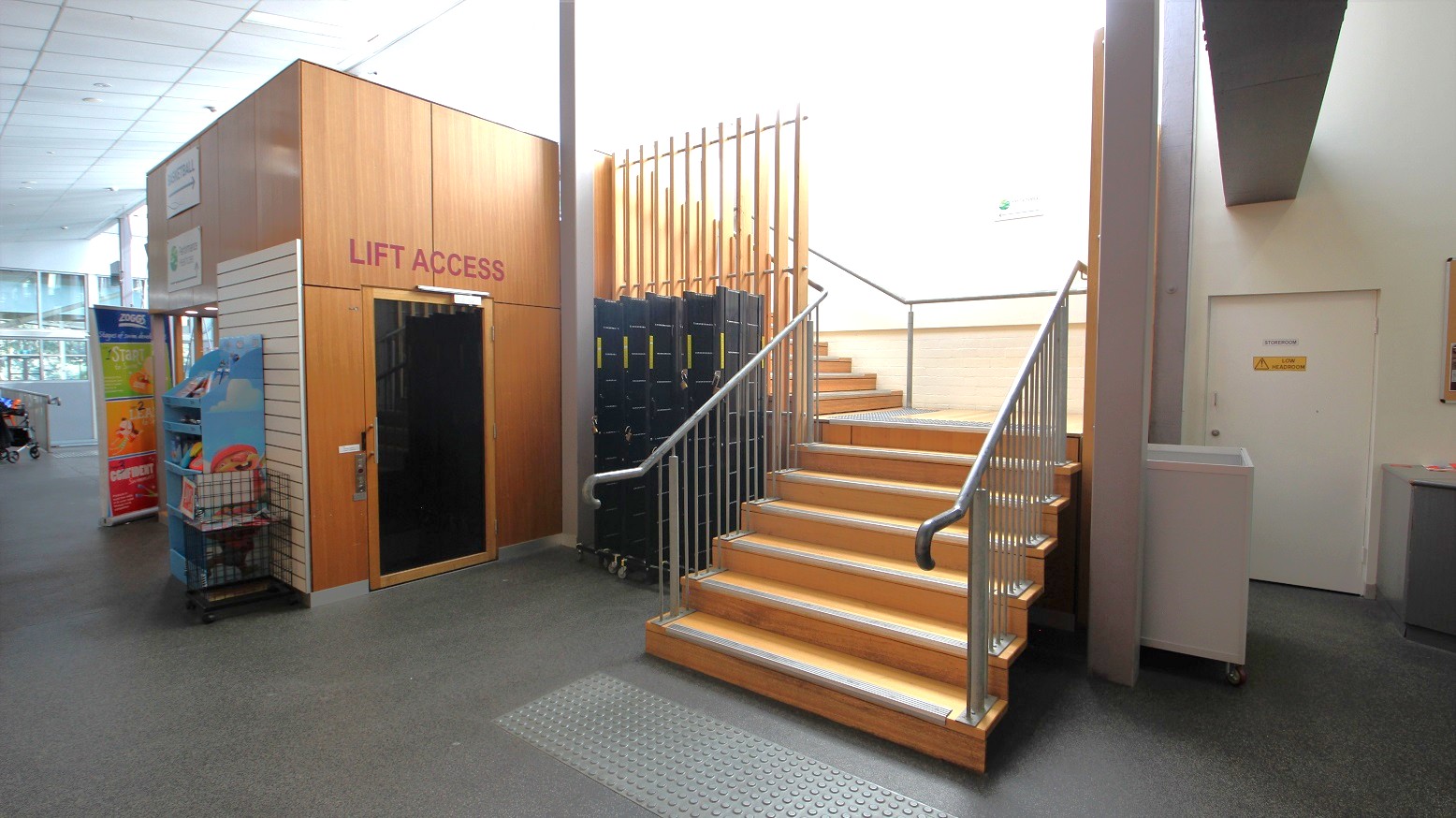 One elevator with a “lift access” sign and a single staircase at the Yoga studio in Eltham Leisure Centre. The staircase has grey metal railings and is beside the storeroom One elevator with a “lift access” sign and a single staircase at the Yoga studio in Eltham Leisure Centre. The staircase has grey metal railings and is beside the storeroom