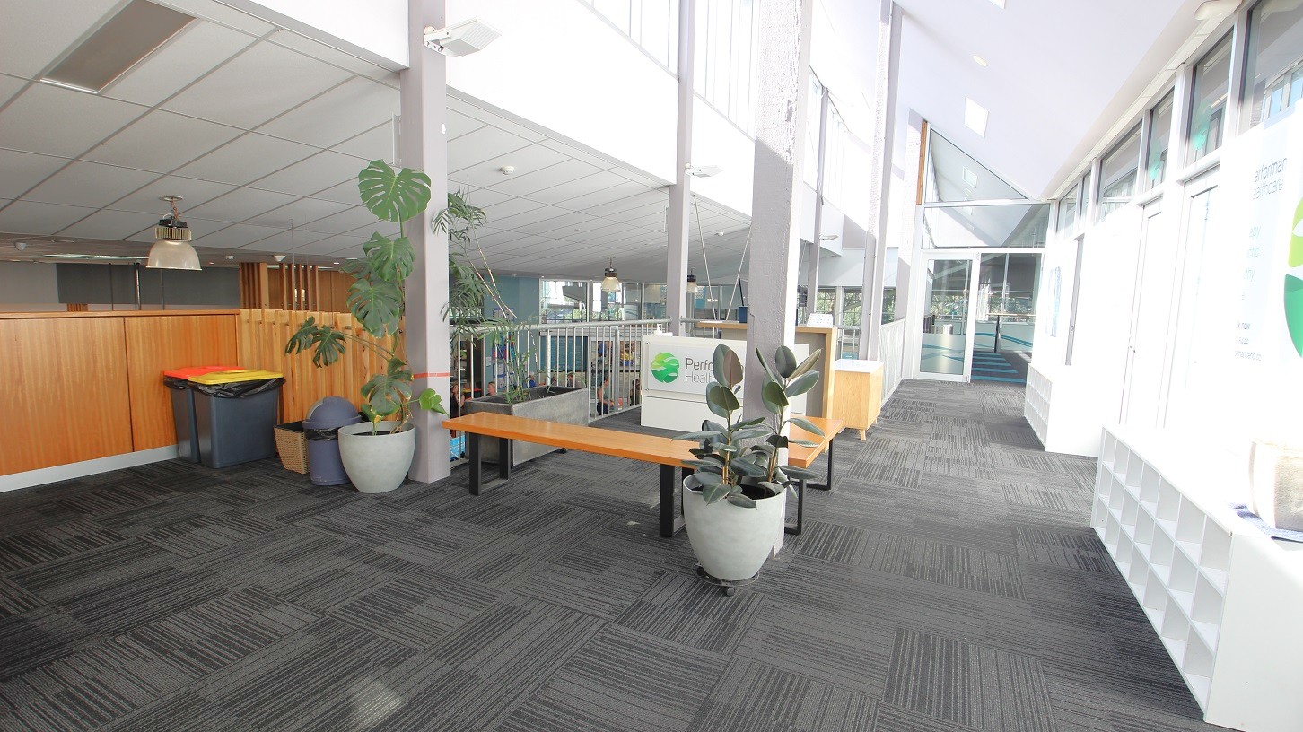 Outside the yoga studio are wood and metal benches, healthy plants, white cabinets, and trash bins. The interior color is white and grey carpet tiles. Outside the yoga studio are wood and metal benches, healthy plants, white cabinets, and trash bins. The interior color is white and grey carpet tiles.