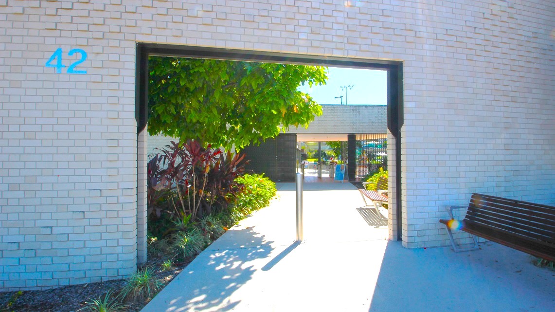 Entrance of the Gympie ARC. As you approach, the white-brick front entrance adorned with stainless steel decorative elements immediately catches your eye, setting a modern and stylish tone. Adjacent to the entrance, there's a metal bench, providing a convenient spot for resting or taking in the surroundings. Notably, the number 42, in a calming blue hue, is affixed to the wall by the front entrance, adding a distinctive touch to the overall design. Entrance of the Gympie ARC. As you approach, the white-brick front entrance adorned with stainless steel decorative elements immediately catches your eye, setting a modern and stylish tone. Adjacent to the entrance, there's a metal bench, providing a convenient spot for resting or taking in the surroundings. Notably, the number 42, in a calming blue hue, is affixed to the wall by the front entrance, adding a distinctive touch to the overall design.