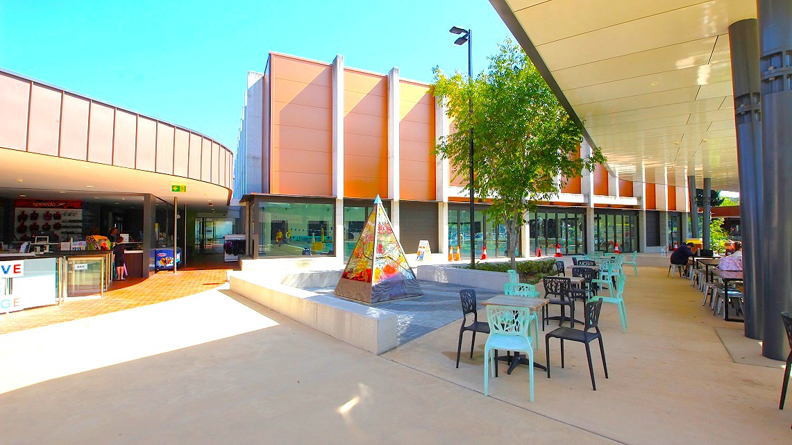 Outdoor area of Gympie Aquatic Recreation Centre. In the center of the area, a quaint small-sized tent stands, providing a focal point. Surrounding it, chairs in various vibrant hues, and tables are strategically placed, creating a cozy seating arrangement. Behind a tree, traffic cones are clearly visible, ensuring safety. Outdoor area of Gympie Aquatic Recreation Centre. In the center of the area, a quaint small-sized tent stands, providing a focal point. Surrounding it, chairs in various vibrant hues, and tables are strategically placed, creating a cozy seating arrangement. Behind a tree, traffic cones are clearly visible, ensuring safety.
