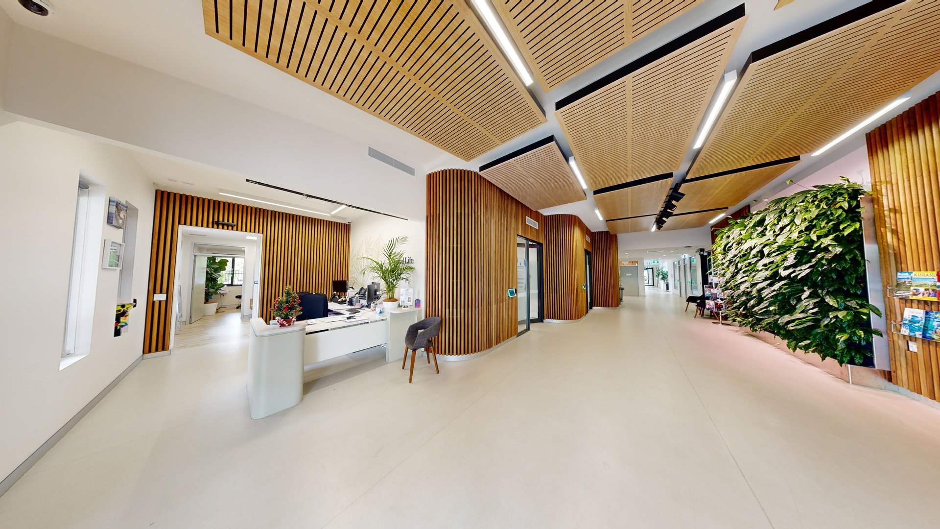 To the left is an automatic glass door adorned with white floral accents. A smaller door on the right provides access to other facilities. Truncated domes and grey non-slip mats are installed before the doors. Posters adorn the walls. The building's wooden interior design is also noticeable. To the left is an automatic glass door adorned with white floral accents. A smaller door on the right provides access to other facilities. Truncated domes and grey non-slip mats are installed before the doors. Posters adorn the walls. The building's wooden interior design is also noticeable.