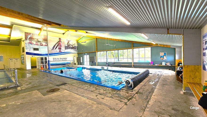 View of the small pool and children's splash area. Huge posters with kids swimming can be seen placed on top of the white wall to the back. A rolled waterproof sheet can be seen at one end of the pool. Near the exit glass doors are two hanging cabinets. Large glass windows on the side allow an appropriate amount of natural light to pass through and give natural scenery of the trees outside. Long brown benches are available throughout the surrounding area of the small pool. View of the small pool and children's splash area. Huge posters with kids swimming can be seen placed on top of the white wall to the back. A rolled waterproof sheet can be seen at one end of the pool. Near the exit glass doors are two hanging cabinets. Large glass windows on the side allow an appropriate amount of natural light to pass through and give natural scenery of the trees outside. Long brown benches are available throughout the surrounding area of the small pool.