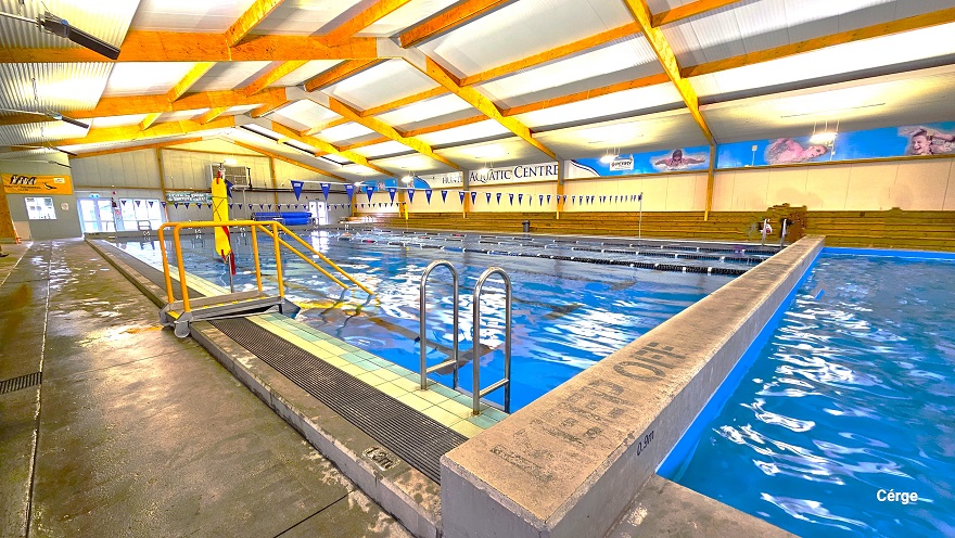 A pool wall divides the large pool and the small pools. On the top surface of this wall is a “Keep Off” phrase in black. Aside from the steel pool ladders, there is also another pool ladder but with small steel tubes of yellow handrails. Strings of triangular blue flags can be seen hanging above the large pool. Long rows of low-brown benches are available on the opposite side of this pool. A pool wall divides the large pool and the small pools. On the top surface of this wall is a “Keep Off” phrase in black. Aside from the steel pool ladders, there is also another pool ladder but with small steel tubes of yellow handrails. Strings of triangular blue flags can be seen hanging above the large pool. Long rows of low-brown benches are available on the opposite side of this pool.
