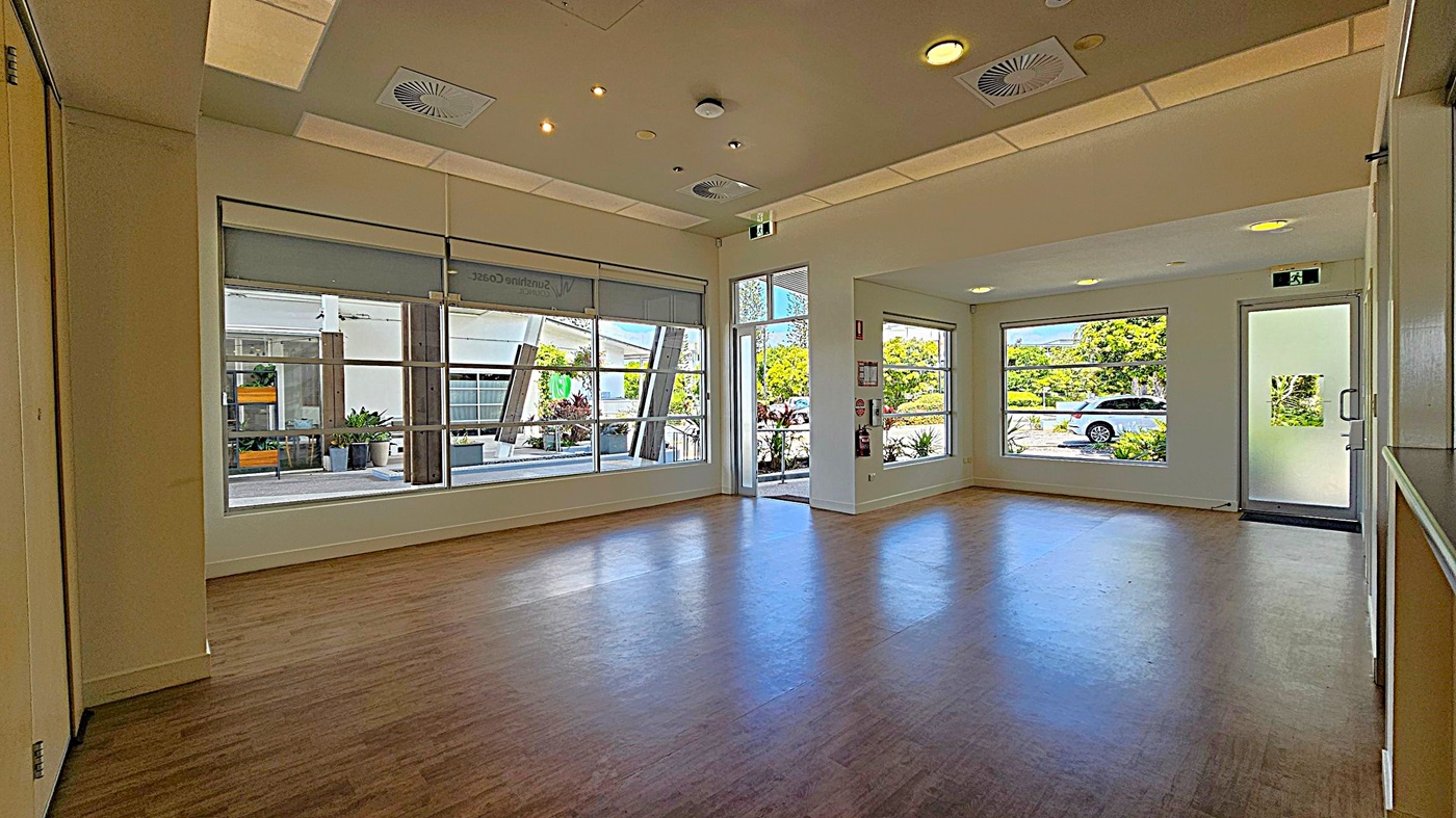 A spacious room with large windows on the left and right, allowing natural light to fill the space. The windows reveal a view of greenery and a parked car outside. The floor is wooden, and the ceiling features recessed lighting and air vents. A glass door on the right leads outside, and there are potted plants visible through the windows. The room has a clean, modern appearance. A spacious room with large windows on the left and right, allowing natural light to fill the space. The windows reveal a view of greenery and a parked car outside. The floor is wooden, and the ceiling features recessed lighting and air vents. A glass door on the right leads outside, and there are potted plants visible through the windows. The room has a clean, modern appearance.