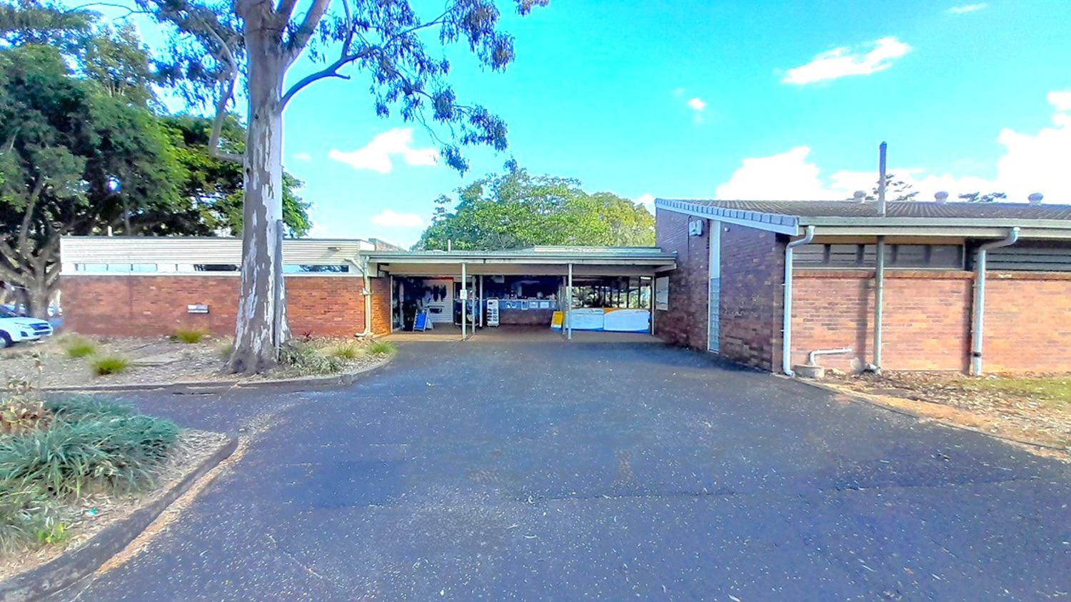 This is the view of the asphalted road with a speed bump facing the centre’s main entrance. A left turn will lead you to the carpark area. A small reception area and a retail store can be found in between the two low set buildings. The facility is made of brown brick walls and surrounded by large trees.