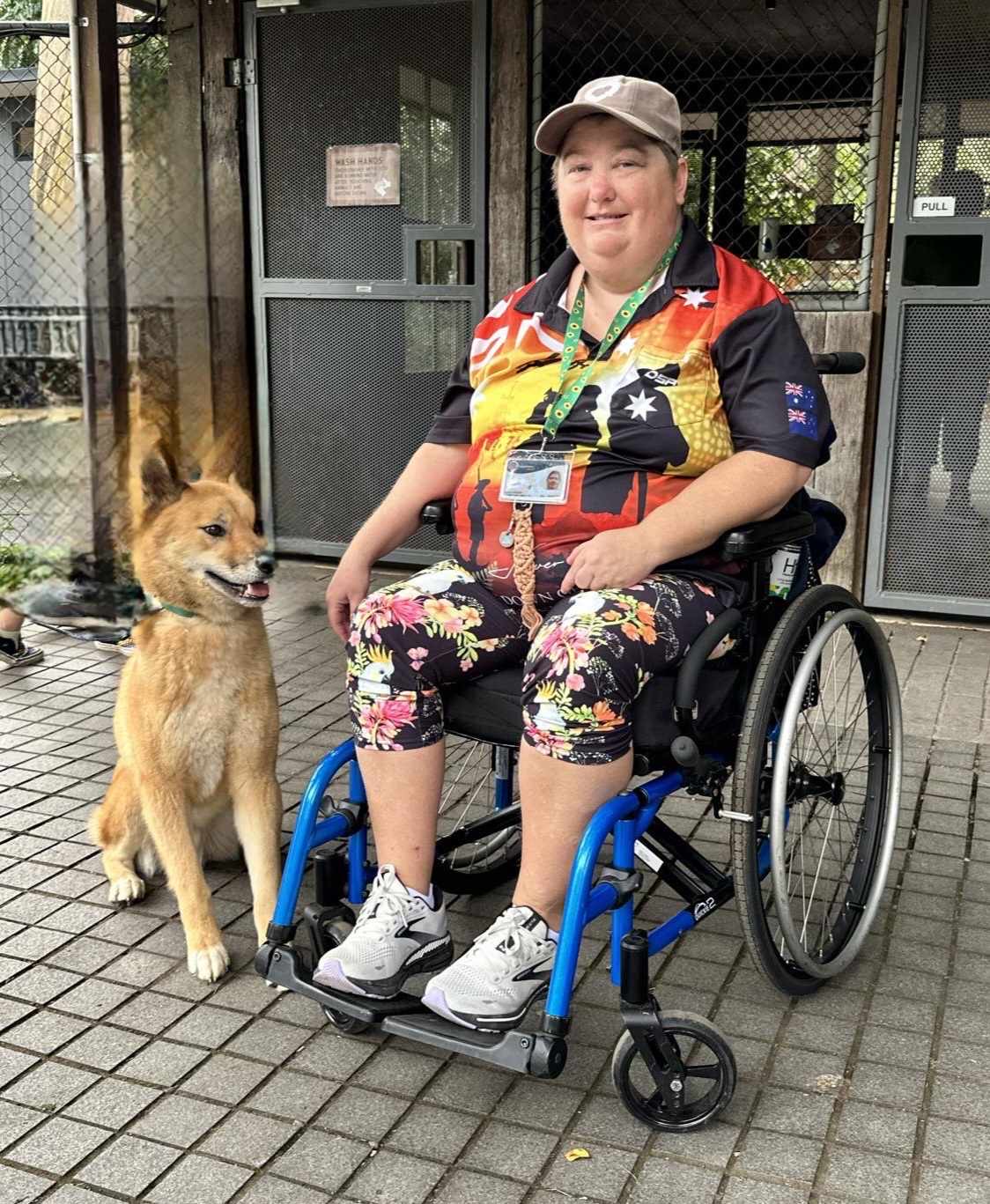A person in a wheelchair with a dog by their side, both outdoors. A person in a wheelchair with a dog by their side, both outdoors.