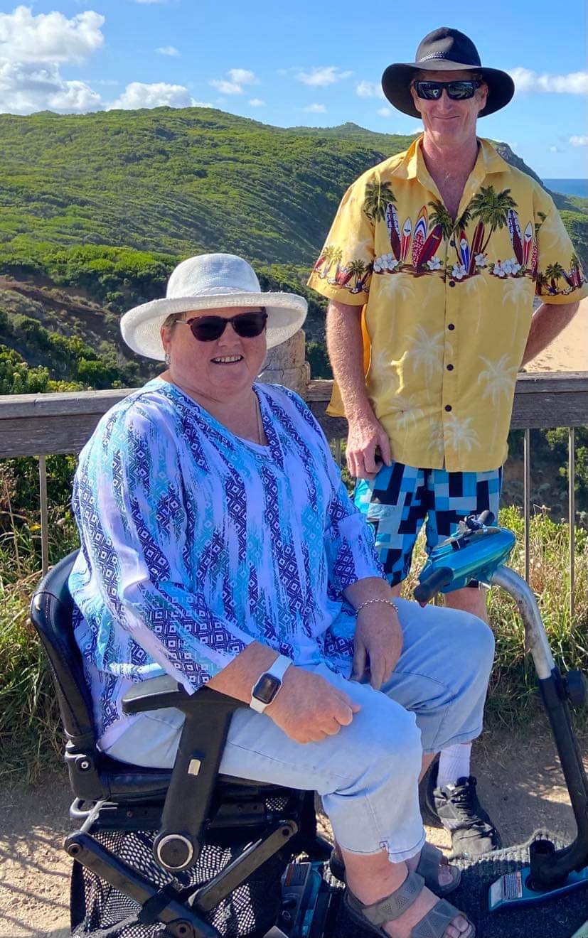 Smiling woman in a sun hat and blue patterned blouse seated outdoors. Smiling woman in a sun hat and blue patterned blouse seated outdoors.