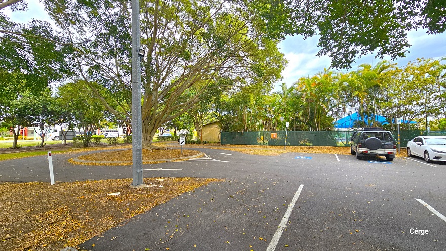 There are two accessible car parking spaces near the entrance to Murrumba Downs Swimming Pool which is close to the green hessian perimeter fence. It has a blue and white logo marking for persons with mobility disabilities. There is a circular garden with a large tree at the end of the car park. A white arrow can be seen on the left pointing inside, and another white arrow pointing outside and back to the carpark area. A road sign for ‘Keep Left’ can be seen in front of the circular garden. There are two accessible car parking spaces near the entrance to Murrumba Downs Swimming Pool which is close to the green hessian perimeter fence. It has a blue and white logo marking for persons with mobility disabilities. There is a circular garden with a large tree at the end of the car park. A white arrow can be seen on the left pointing inside, and another white arrow pointing outside and back to the carpark area. A road sign for ‘Keep Left’ can be seen in front of the circular garden.