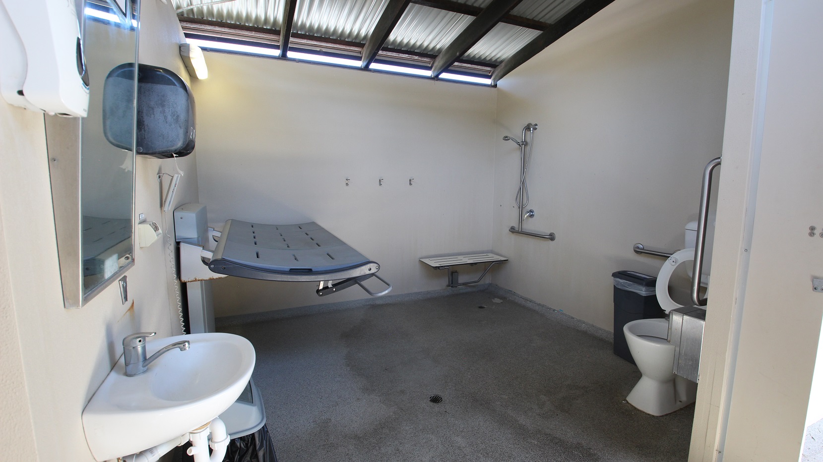 An adult size change table is located next to the Indoor 25m pool.  A functional room including the table and toilet with a significant number of handrails and supports.