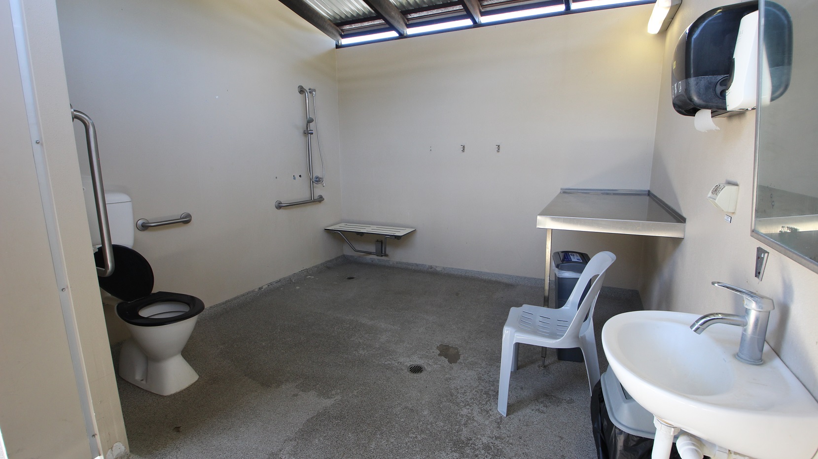 An adult size change table is located next to the Indoor 25m pool.  A functional room including the table and toilet with a significant number of handrails and supports.