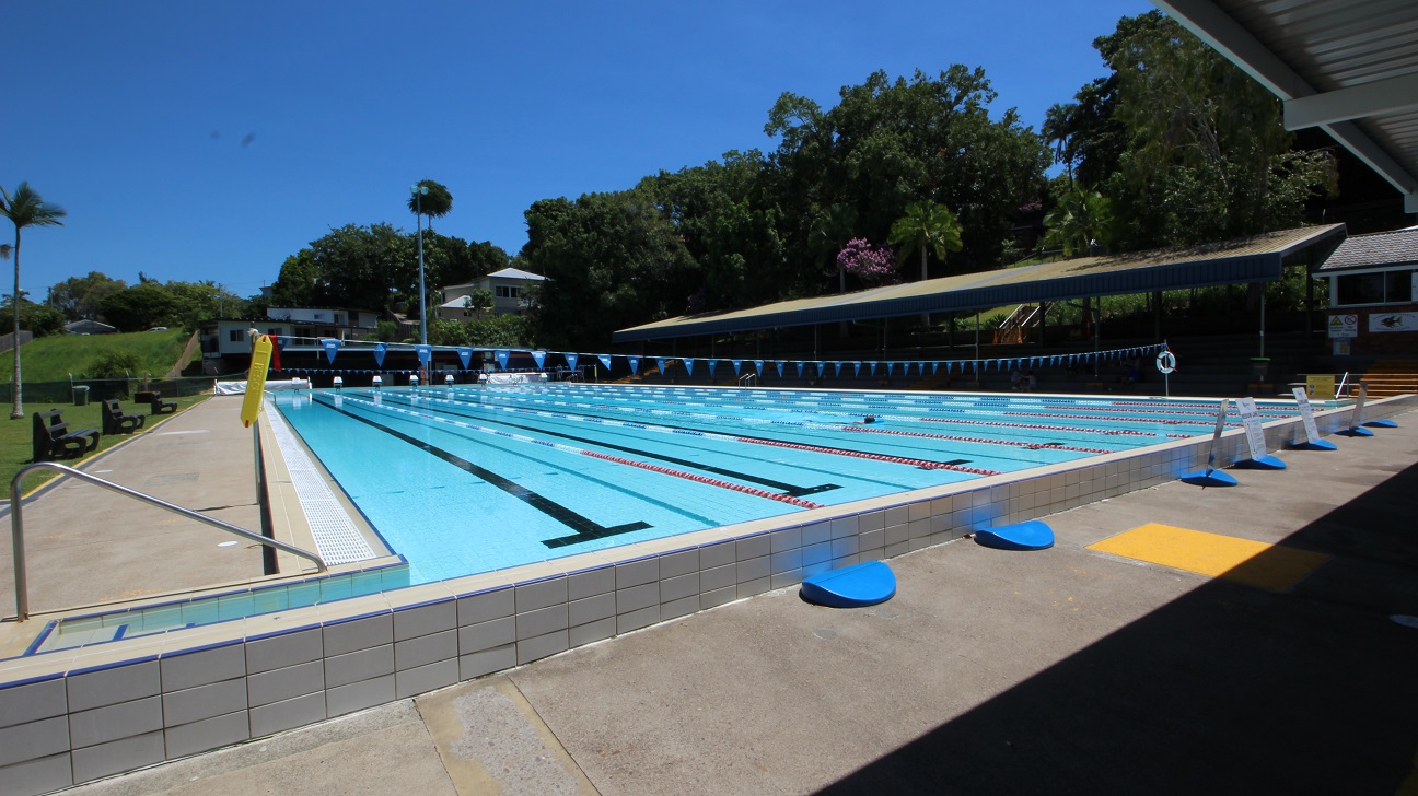 The outdoor 50m pool at the Nambour Aquatic Centre. The pool is 8 lanes wide and set amongst dense green foliage and a spectator stand on the far side of the pool.