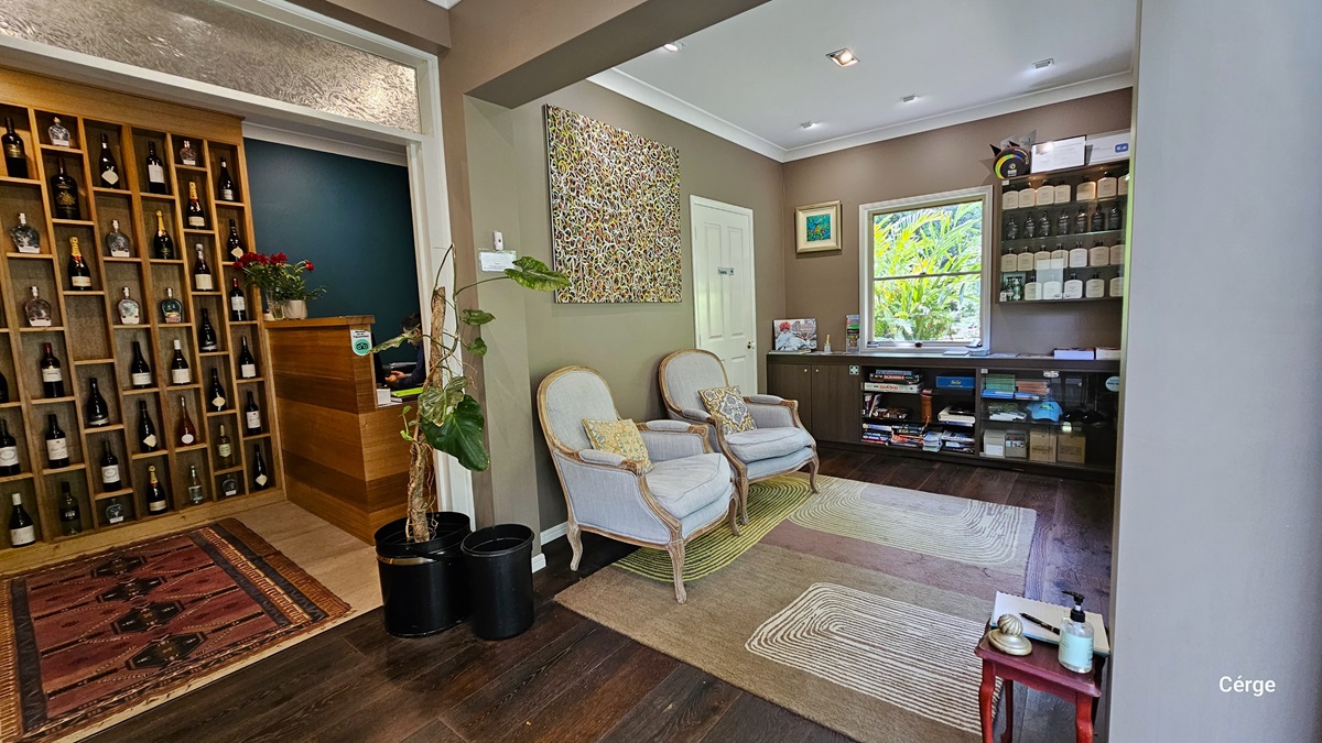 Upon entering Narrows Escape Rainforest Retreat's reception, a wall displays various wines near the desk, with a carpet in front. Two cushioned white chairs are against the right wall. A cabinet holds tourism info, retail items, and awards details. A small tea table is in the corner. The ceiling has a white cove design, and the wall is almond and vintage brown. An abstract art painting is on the wall. The floor is timber, partially covered with an intricate carpet. Upon entering Narrows Escape Rainforest Retreat's reception, a wall displays various wines near the desk, with a carpet in front. Two cushioned white chairs are against the right wall. A cabinet holds tourism info, retail items, and awards details. A small tea table is in the corner. The ceiling has a white cove design, and the wall is almond and vintage brown. An abstract art painting is on the wall. The floor is timber, partially covered with an intricate carpet.