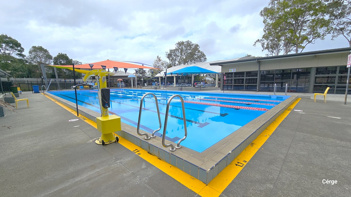25m, 4-lane pool at Nerang Aquatic Centre. A yellow line is painted around the pool with a 1.1m label indicating the depth of the pool. There is a yellow pool hoist on the left side of the pool. Several pool ladders are placed all around the pool sides. Yellow waterproof plastic chairs are available on the pool deck. There is a beige, yellow, and light green shade sails at the end of the pool. 25m, 4-lane pool at Nerang Aquatic Centre. A yellow line is painted around the pool with a 1.1m label indicating the depth of the pool. There is a yellow pool hoist on the left side of the pool. Several pool ladders are placed all around the pool sides. Yellow waterproof plastic chairs are available on the pool deck. There is a beige, yellow, and light green shade sails at the end of the pool.