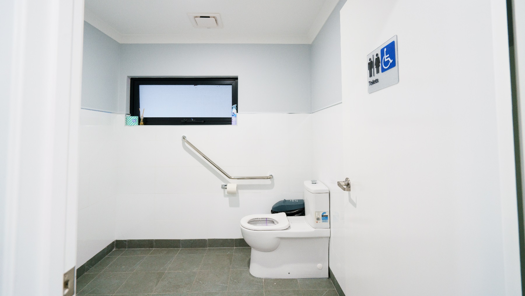 The clinic’s toilet is almost all-white including the door, except the rails of the window which are painted black. This is an all-gender toilet as signified by the signage posted on the door. The toilet is wide enough to accommodate anyone, even guests with disabilities. There’s a rubbish bin in the corner and a roll of tissue paper mounted on the wall. There is also a stainless grab rail situated next to the toilet. The clinic’s toilet is almost all-white including the door, except the rails of the window which are painted black. This is an all-gender toilet as signified by the signage posted on the door. The toilet is wide enough to accommodate anyone, even guests with disabilities. There’s a rubbish bin in the corner and a roll of tissue paper mounted on the wall. There is also a stainless grab rail situated next to the toilet.