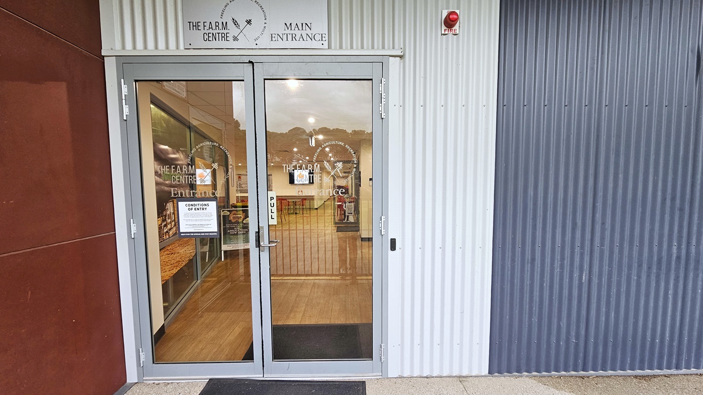 Entrance to the building is through a manual outward-opening door equipped with a non-slippery mat. Facility signage is placed on the wall. Posters and conditions of entry are affixed to the glass door along with stickers bearing the facility name. To the left is a concrete wall painted in brown, while on the right is a wall with corrugated design in dark grey. A fire safety light is placed on top. Entrance to the building is through a manual outward-opening door equipped with a non-slippery mat. Facility signage is placed on the wall. Posters and conditions of entry are affixed to the glass door along with stickers bearing the facility name. To the left is a concrete wall painted in brown, while on the right is a wall with corrugated design in dark grey. A fire safety light is placed on top.