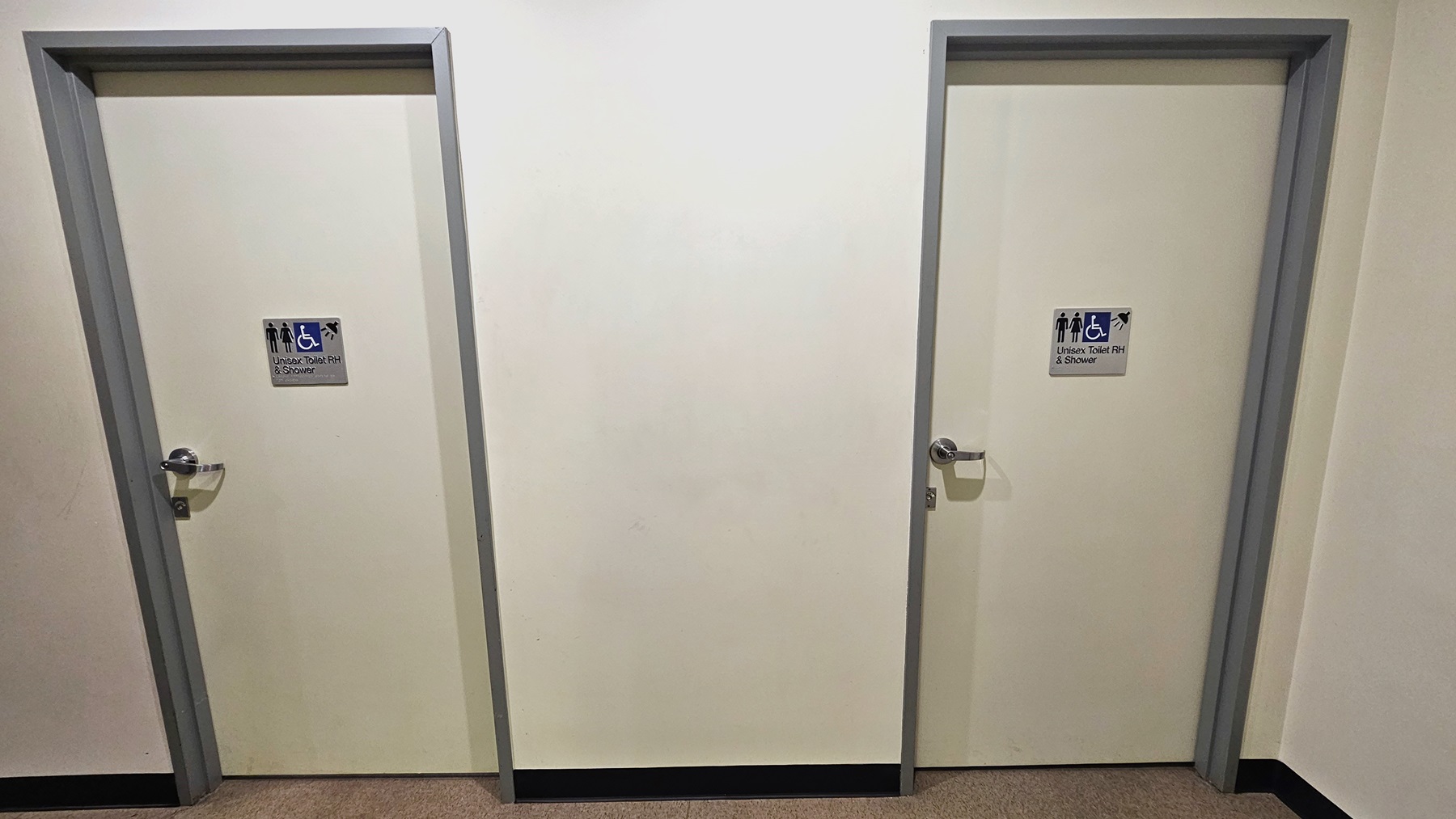 There are two accessible all-gender bathrooms with showers located near the gymnasium. Each white door is marked with signage in front. There are two accessible all-gender bathrooms with showers located near the gymnasium. Each white door is marked with signage in front.