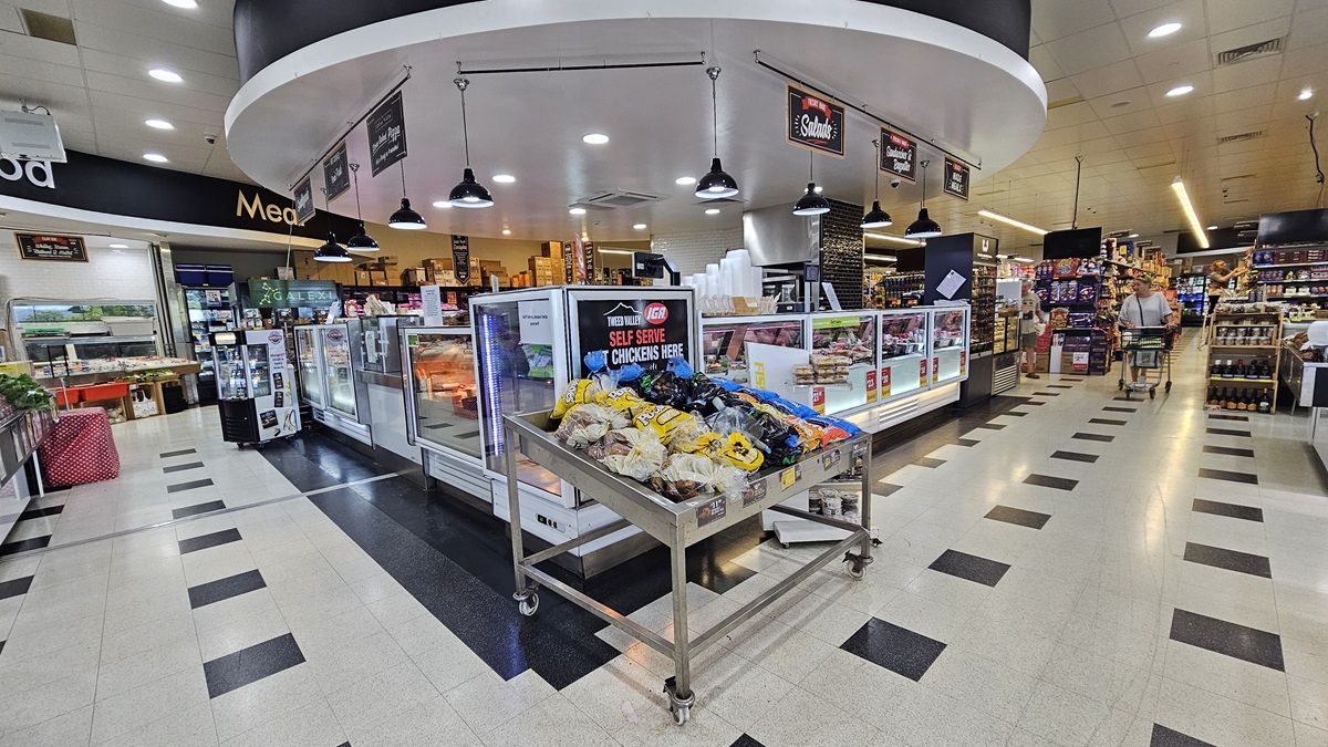 A closer look at the Delicatessen section. “Self-serve chickens” are visibly placed in the center of the Delicatessen near a steel cart loaded with products. Consumers are apparent on the right side corner adjacent to the three-layer shelves. Fluorescent lights and banners overcome the ceiling of the Delicatessen section. Striking black tiles conquer both sides of the area as well. A closer look at the Delicatessen section. “Self-serve chickens” are visibly placed in the center of the Delicatessen near a steel cart loaded with products. Consumers are apparent on the right side corner adjacent to the three-layer shelves. Fluorescent lights and banners overcome the ceiling of the Delicatessen section. Striking black tiles conquer both sides of the area as well.