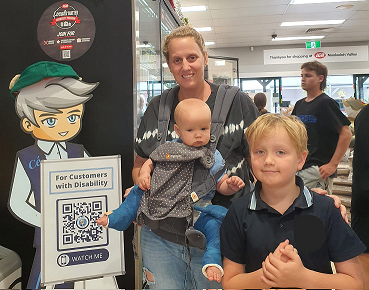 A woman with a baby and a young boy stands beside a Cérge cartoon cutout at a store.