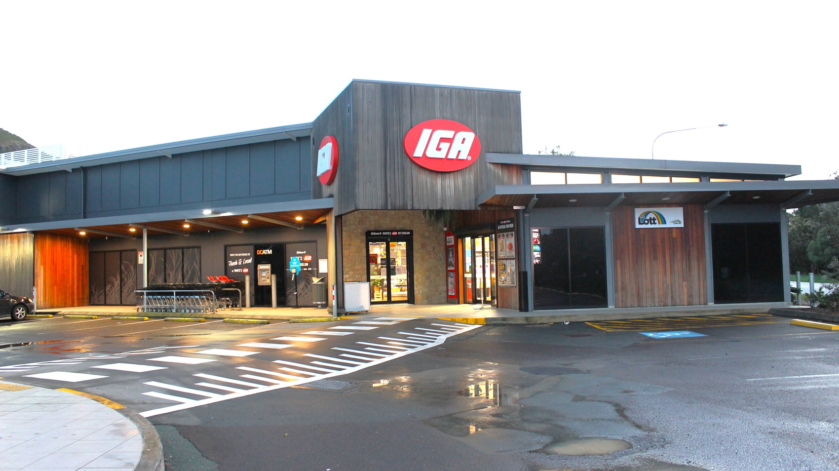 White's IGA Mt Coolum has a red oval-shaped sign with white IGA letters located on the façade. The building design is modern and is painted with grey and brown. There are shopping trolleys available outside the store and an ATM. There are also several parking spaces in front of the building indicated by painted white lines that served as space partitions for each car. There is an accessible car parking space available directly outside the store. White's IGA Mt Coolum has a red oval-shaped sign with white IGA letters located on the façade. The building design is modern and is painted with grey and brown. There are shopping trolleys available outside the store and an ATM. There are also several parking spaces in front of the building indicated by painted white lines that served as space partitions for each car. There is an accessible car parking space available directly outside the store.