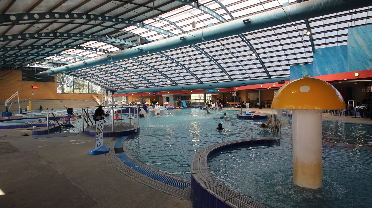 Adults and children are enjoying their bonding time at the children’s pool. Aside from the mushroom fountain, there are metal tubes spurting a standard flow of water on the edges of the pool. A no-diving sign is also placed to caution all the guests. Visible further to the back of the image is a digital clock and a white hoist sling for lifting persons with mobility disabilities. Adults and children are enjoying their bonding time at the children’s pool. Aside from the mushroom fountain, there are metal tubes spurting a standard flow of water on the edges of the pool. A no-diving sign is also placed to caution all the guests. Visible further to the back of the image is a digital clock and a white hoist sling for lifting persons with mobility disabilities.