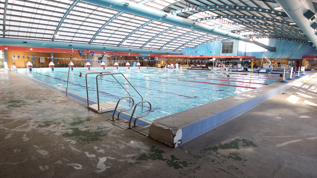 View of another end of the 8-lane 25m lap pool. The elevated section on the edge of the pool is made of blue tiles on the side, while on the top are diamond and triangular designs. Beside the pool ladder is a small white platform and metal handrail. View of another end of the 8-lane 25m lap pool. The elevated section on the edge of the pool is made of blue tiles on the side, while on the top are diamond and triangular designs. Beside the pool ladder is a small white platform and metal handrail.