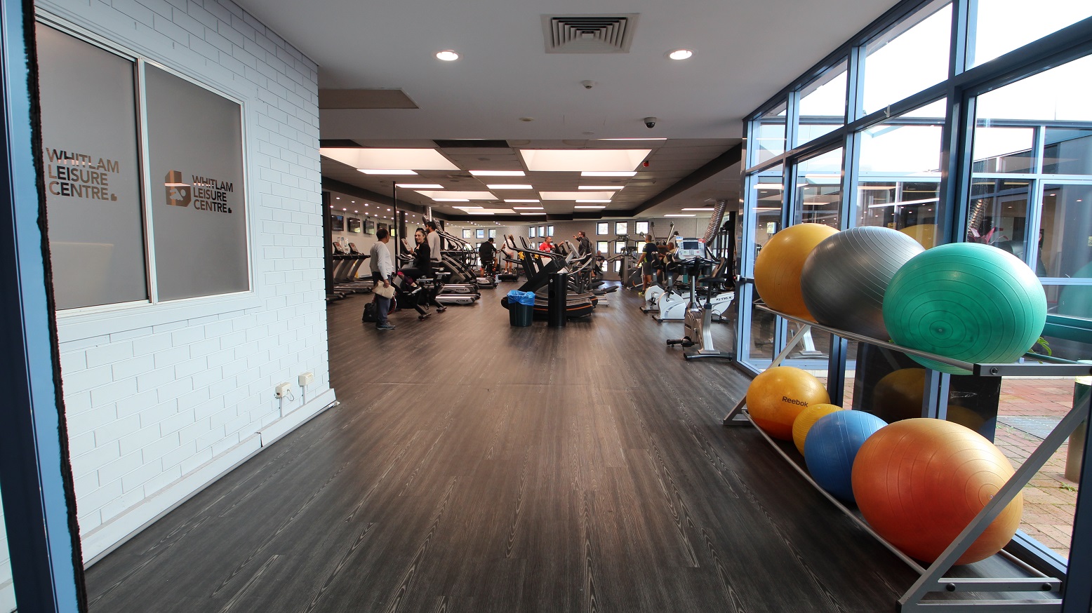 Left of the narrow corridor leading to the fitness facility is made of a white brick wall, while on the opposite side are glass walls and gym balls arranged in two layers of metal platforms. The first machines that guests could see were treadmills. The room is well-lit by square lights at the ceilings. Left of the narrow corridor leading to the fitness facility is made of a white brick wall, while on the opposite side are glass walls and gym balls arranged in two layers of metal platforms. The first machines that guests could see were treadmills. The room is well-lit by square lights at the ceilings.